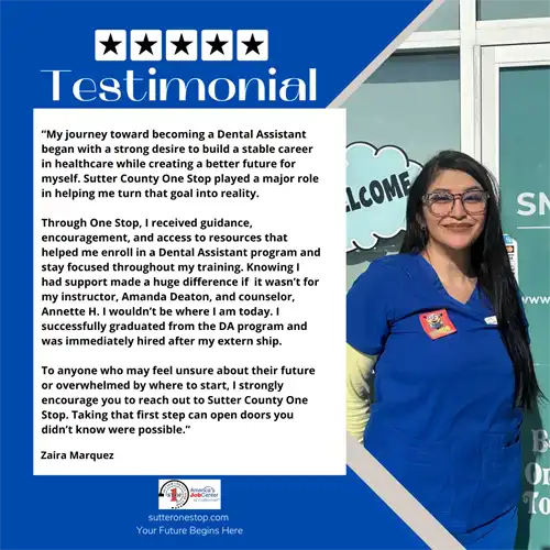 A female wearing blue scrubs and glasses standing in front of a building. 