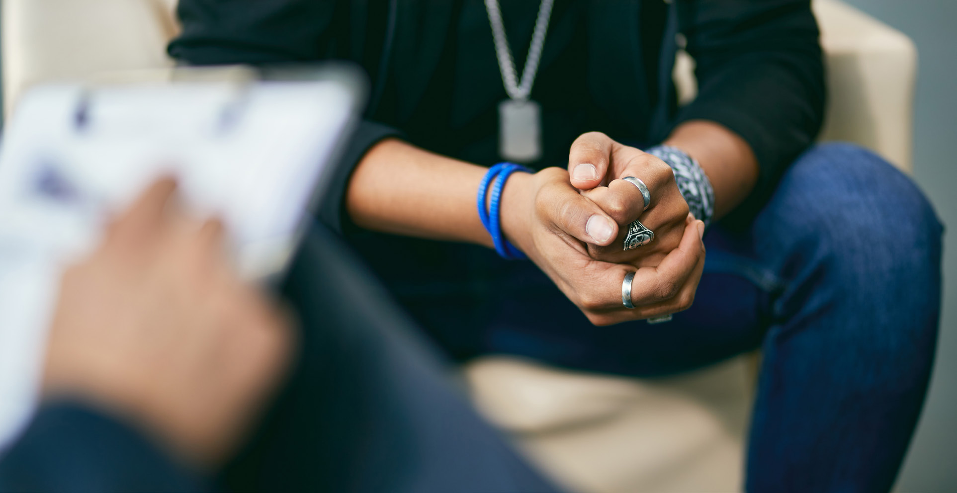 Photo of person with clipboard in foreground with student sitting