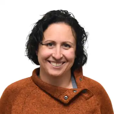 Woman with dark, curly, short hair smiling