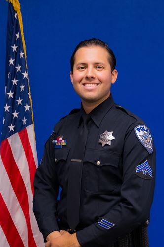 police officer standing by american flag smiling