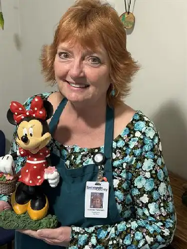 Adult in green apron holding a ceramic Minnie Mouse