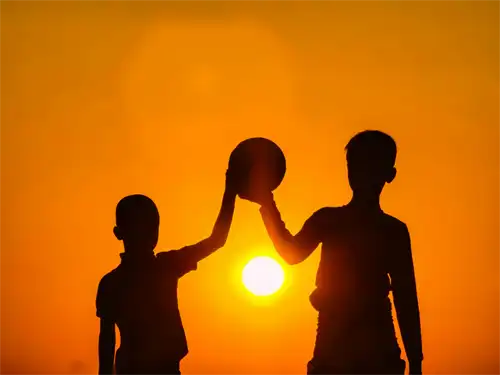 two boys in sun with ball
