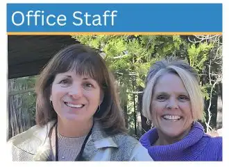 Face shot of a blonde and a brunette smiling in the forest