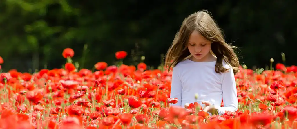 An artistic photo of a young girl walking in a field of flowers.