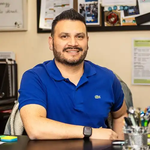 man sitting at desk with arm resting on desk smiling