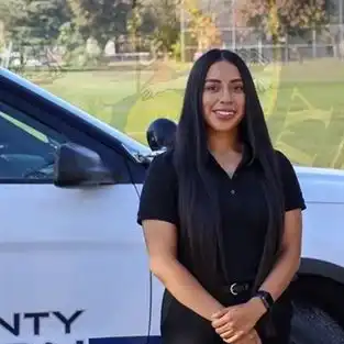 Karina standing in uniform in front of a Madera Count police car.