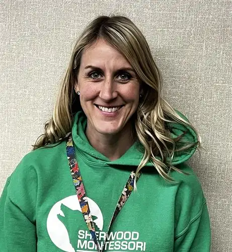 blond haired woman smiling wearing a green Sherwood sweatshirt