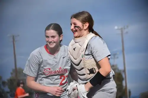 Two softball players laughing together after a good play