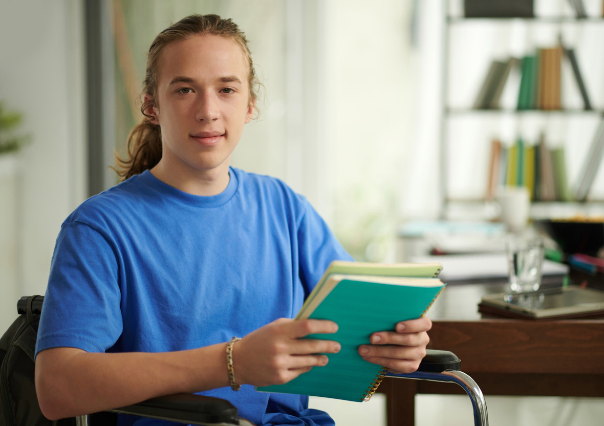 Portrait of high school student with disability studying in library