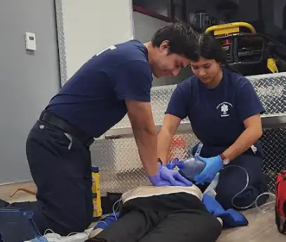 Two EMT students simulate working on resuscitating a victim at a scene 