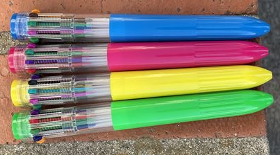 four multi-color click pens against a brick background
