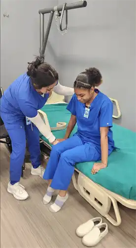 CNA students help each other practice necessary skills in the classroom