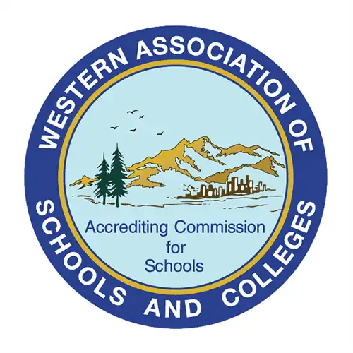 Circular Western Association of Schools and Colleges (WASC) Accrediting Commission for Schools logo. The blue and white seal features a mountain landscape, evergreen trees, birds, and a city skyline, with the organization’s name around the outer edge.