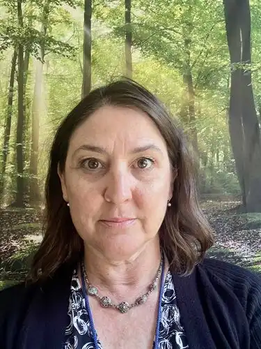 woman with shoulder length brown hair and hazel eyes forest background