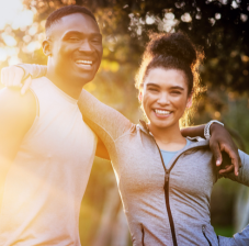 Man and woman wearing workout clothes and smiling outside