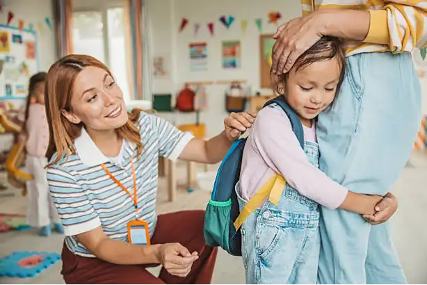 Child holding onto parent's leg with teacher
