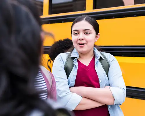 Older Student Standing in Front of a Bus