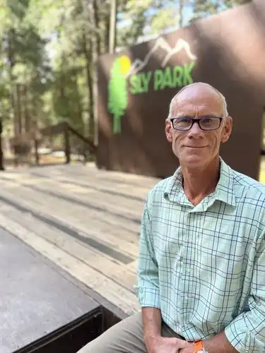 Smiling man with glasses in front of an outdoor stage