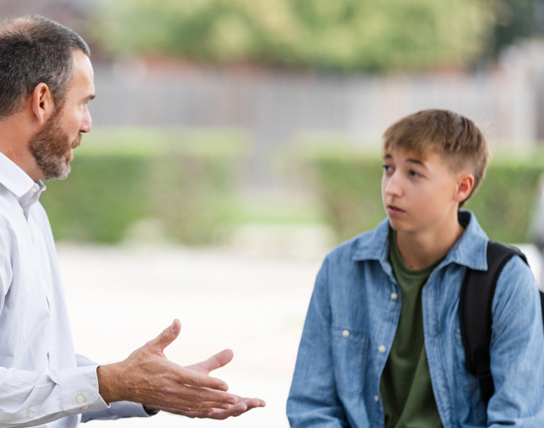 Photo of adult talking to a student outside