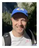 Face shot of a man grinning in a blue ball cap and a white shirt