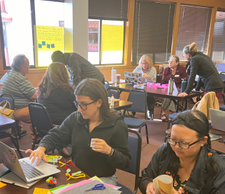 Teachers in groups doing professional development at laptops